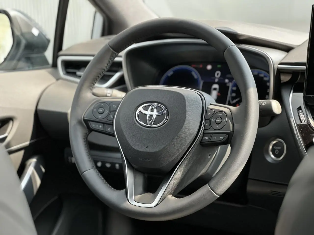 Volant multifonction noir de la Toyota Corolla Touring Sport 1.8 Hybrid 2025, vue rapprochée côté conducteur.