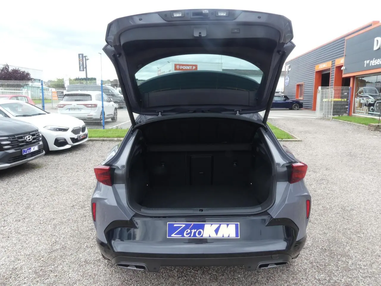 Vue arrière d'un CUPRA Formentor gris Graphène avec coffre ouvert et double sortie d'échappement noire visible.