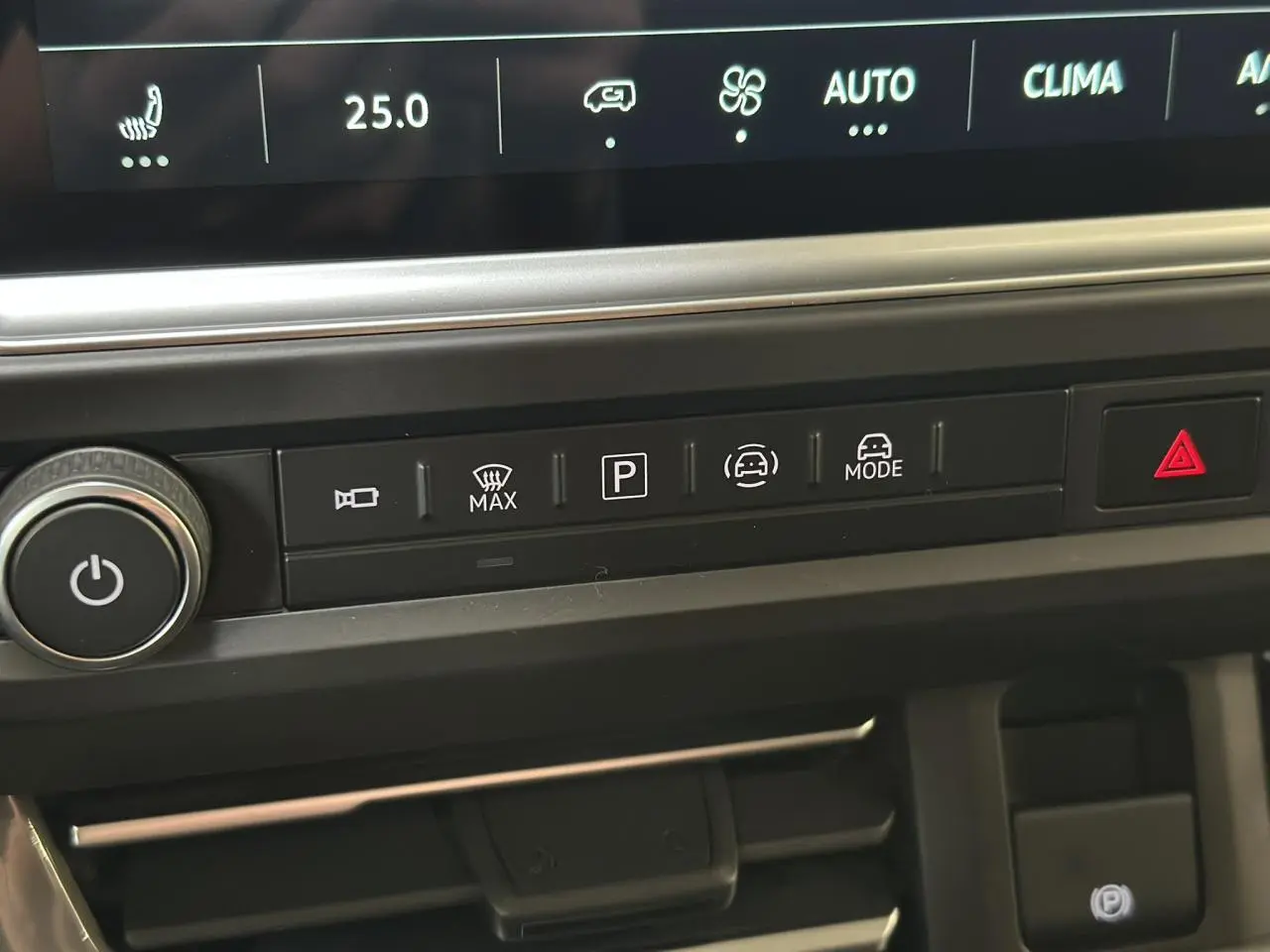 Gros plan sur la console centrale du Volkswagen Transporter T7 noir, montrant les commandes de climatisation et d’aide à la conduite.