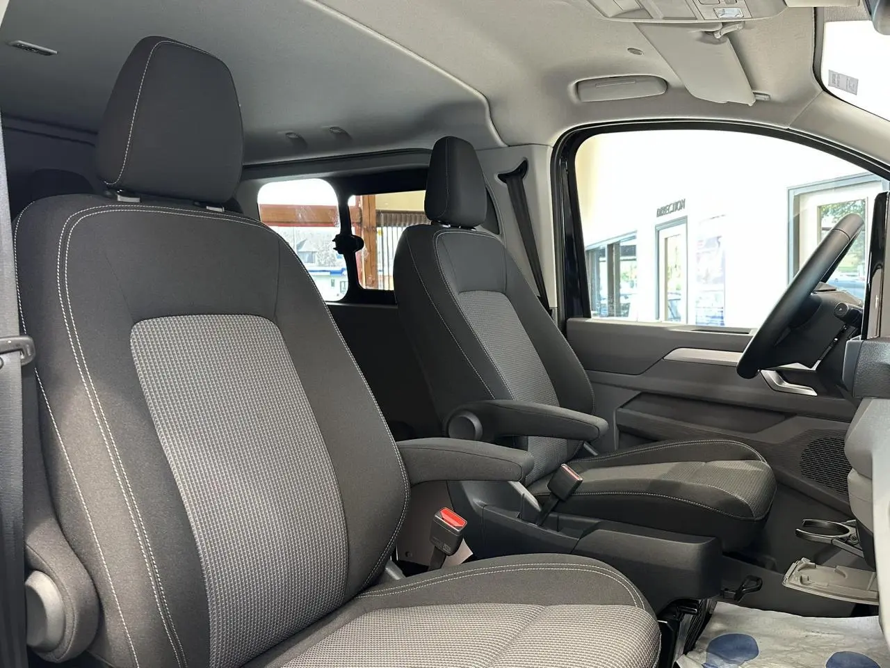 Vue intérieure côté droit du Volkswagen Transporter T7 ProCab 2026, sièges tissu à rayures gris et noir.