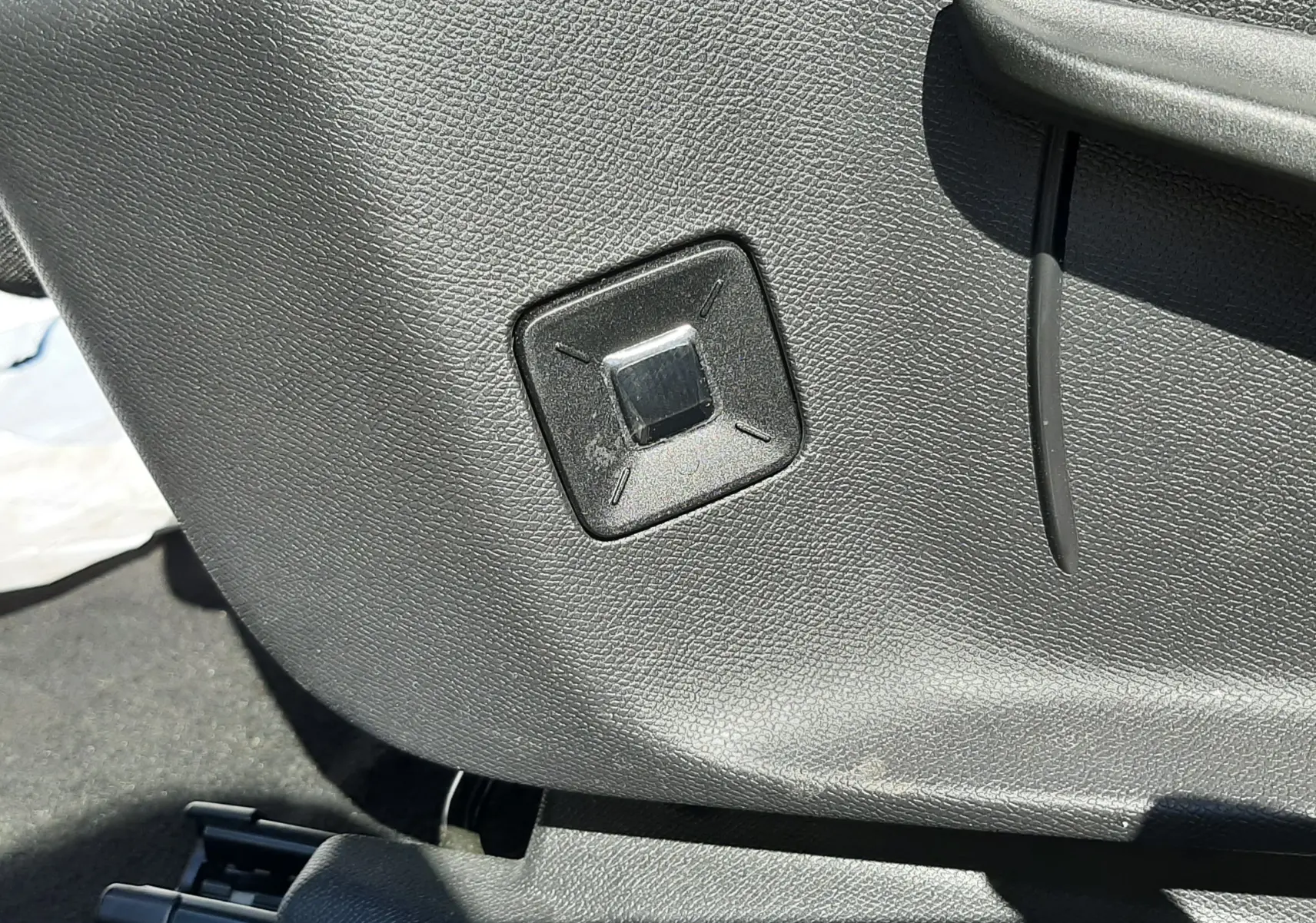 Détail du bouton de réglage électrique du siège en plastique noir à l'intérieur du Peugeot 3008 blanc Okenite.
