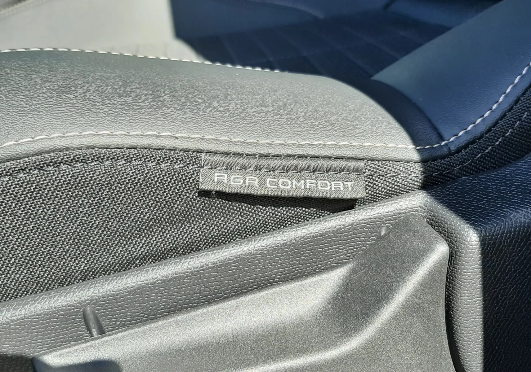 Détail de la manette de réglage d'assise avec étiquette AGR Comfort sur siège tissu et cuir noir du Peugeot 3008 blanc.