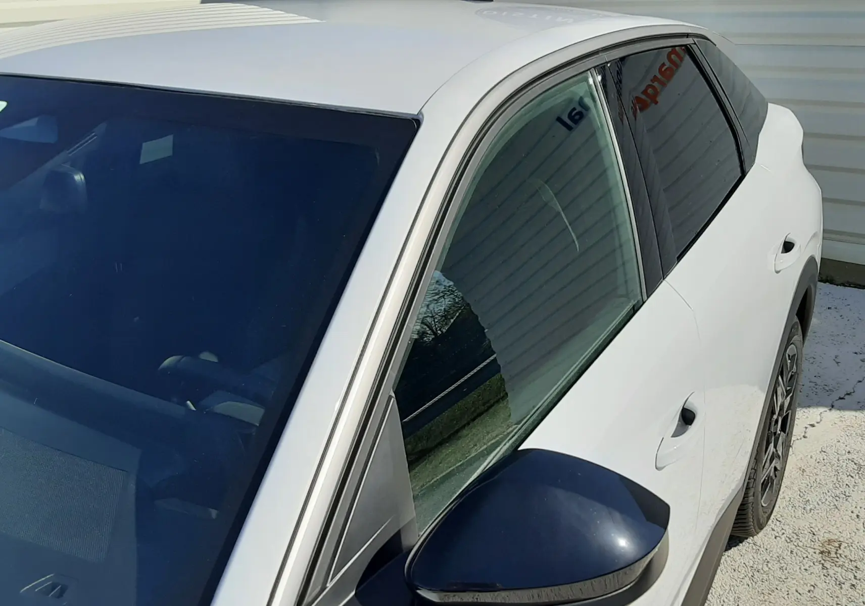 Vue 3/4 avant droit du Peugeot 3008 blanc Okenite, mettant en valeur le rétroviseur noir et les vitres teintées.