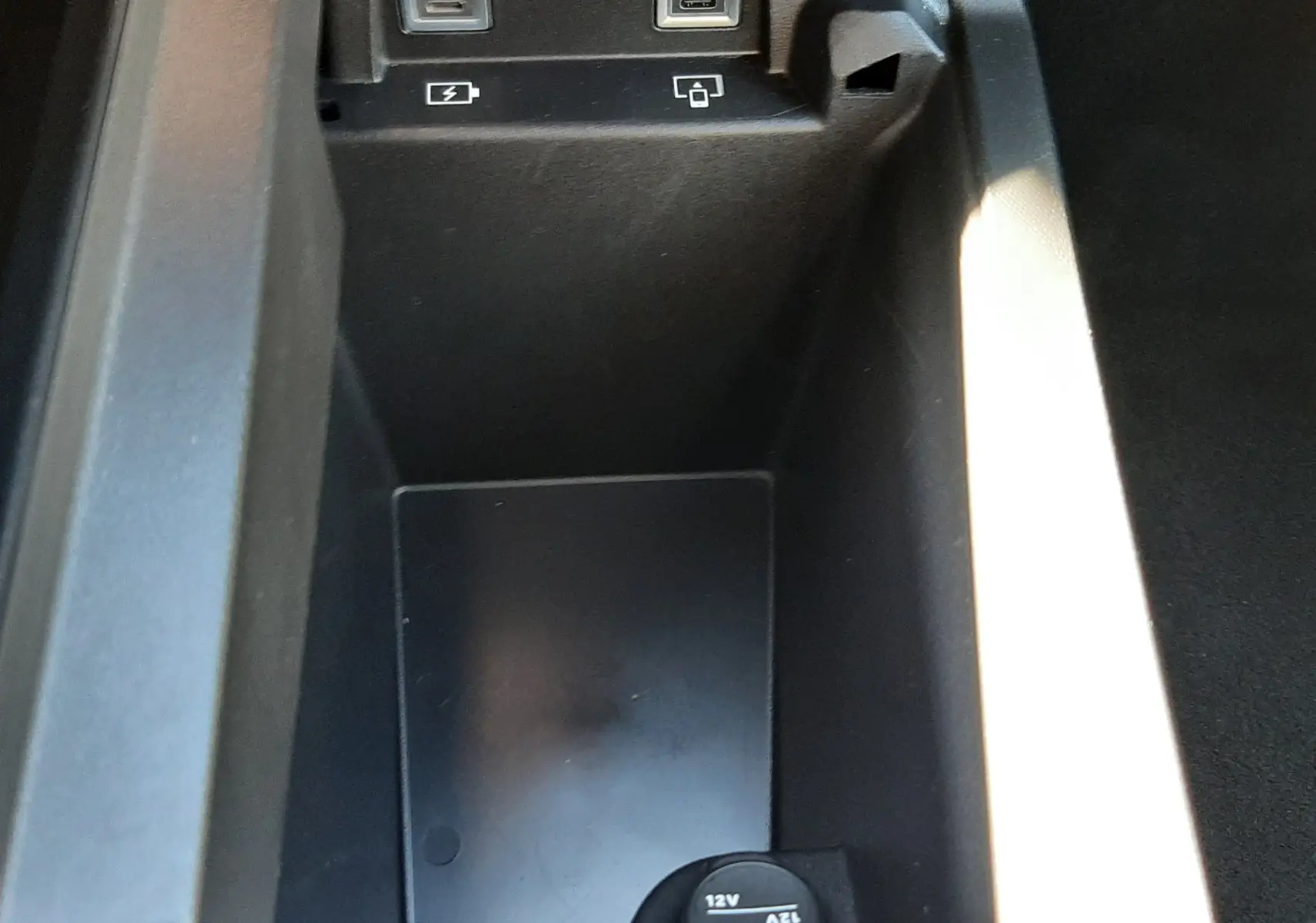Vue rapprochée de la console centrale noire du Peugeot 3008 HYBRID 2024 avec ports USB et prise 12V visibles.