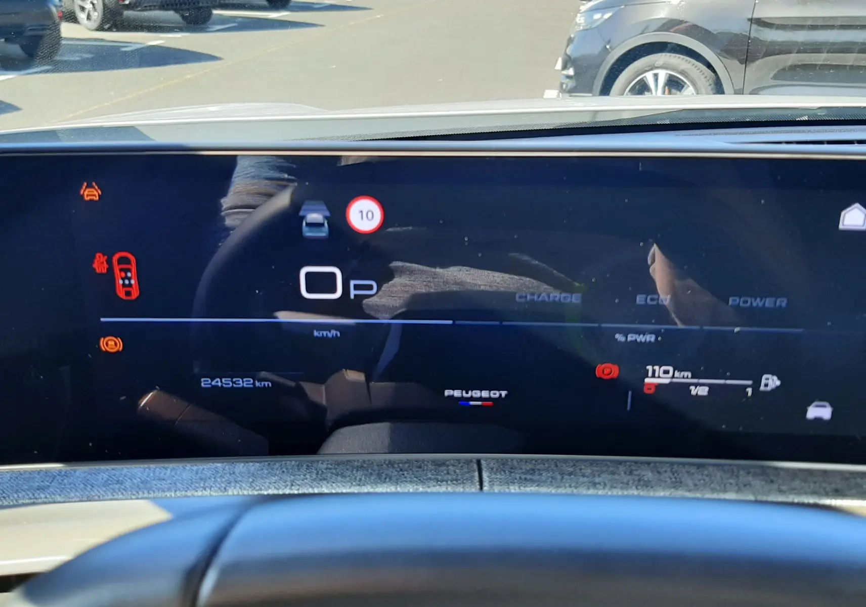 Vue intérieure du tableau de bord numérique du Peugeot 3008 blanc, affichant la vitesse à 0 km/h et les alertes de sécurité.
