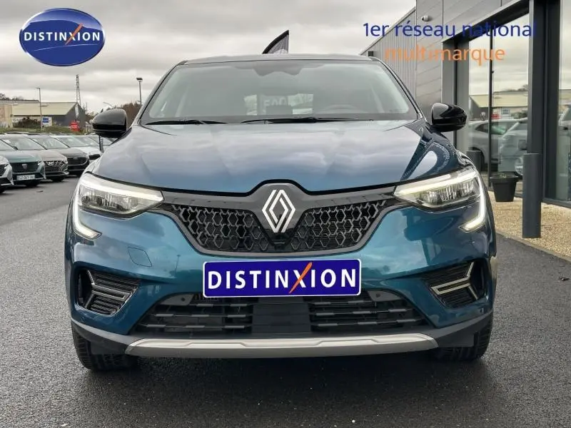 Vue frontale d'un Renault Arkana 2025 bleu Zanzibar avec calandre noire et feux LED allumés.