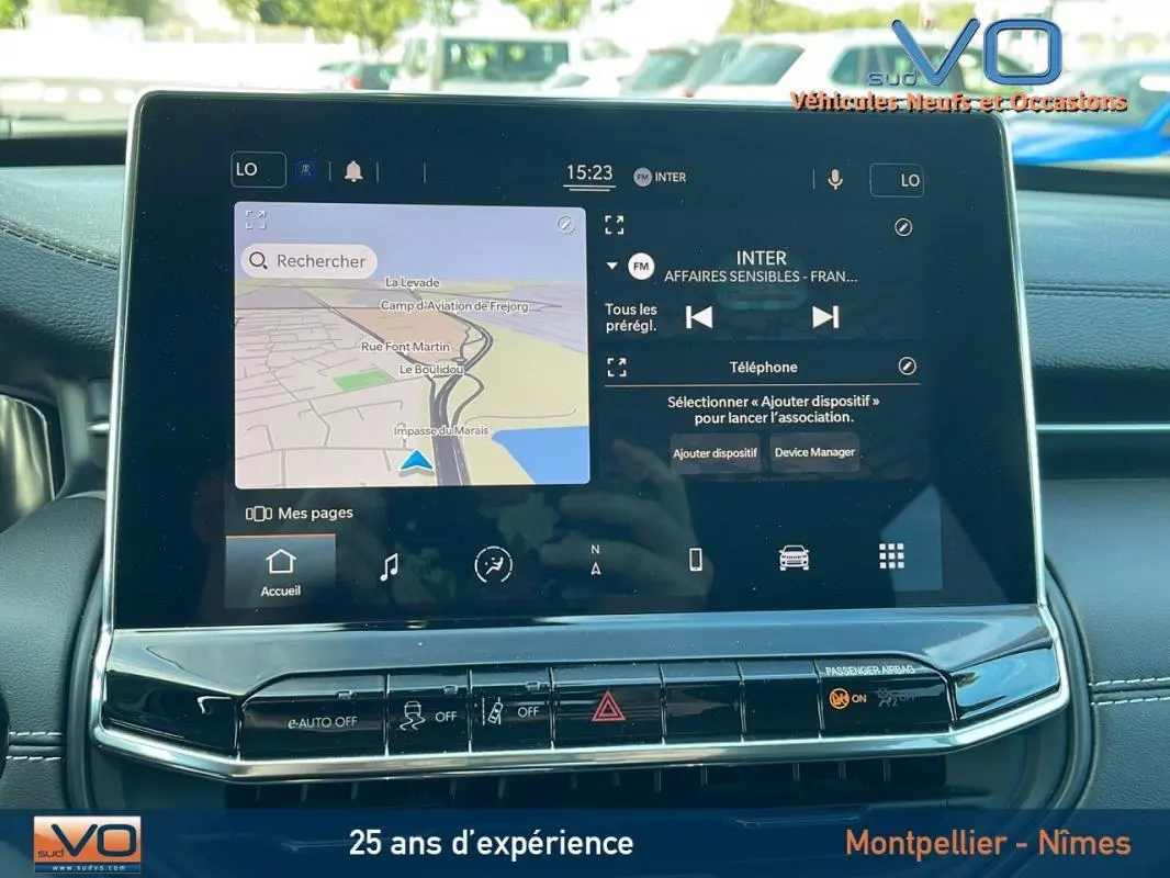 Écran tactile central du Jeep Compass 2023 affichant navigation et radio, avec tableau de bord noir en arrière-plan.