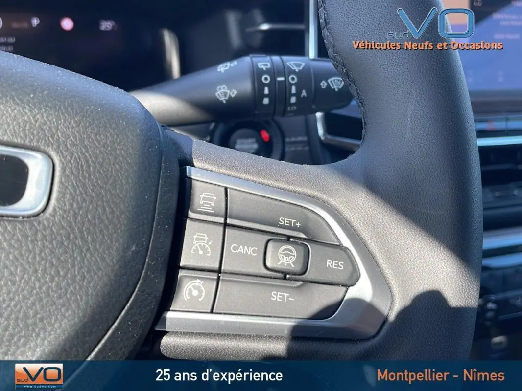 Gros plan sur les commandes au volant du Jeep Compass 2023 noir, mettant en valeur les boutons du régulateur de vitesse.