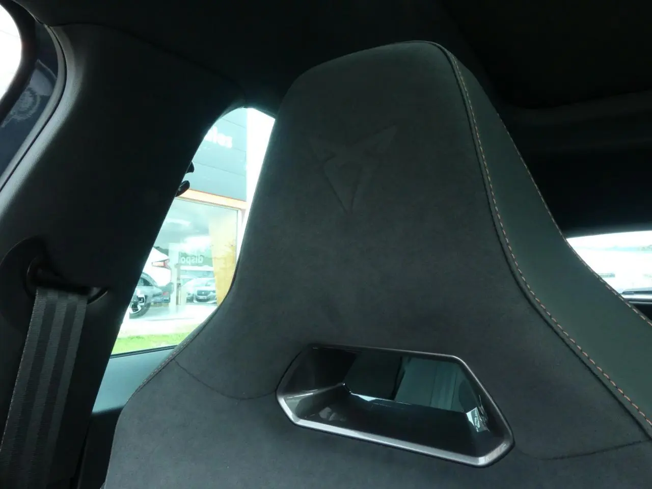 Détail du siège baquet noir suédine avec surpiqûres cuivrées et logo Cupra embossé, intérieur du Formentor gris graphene.