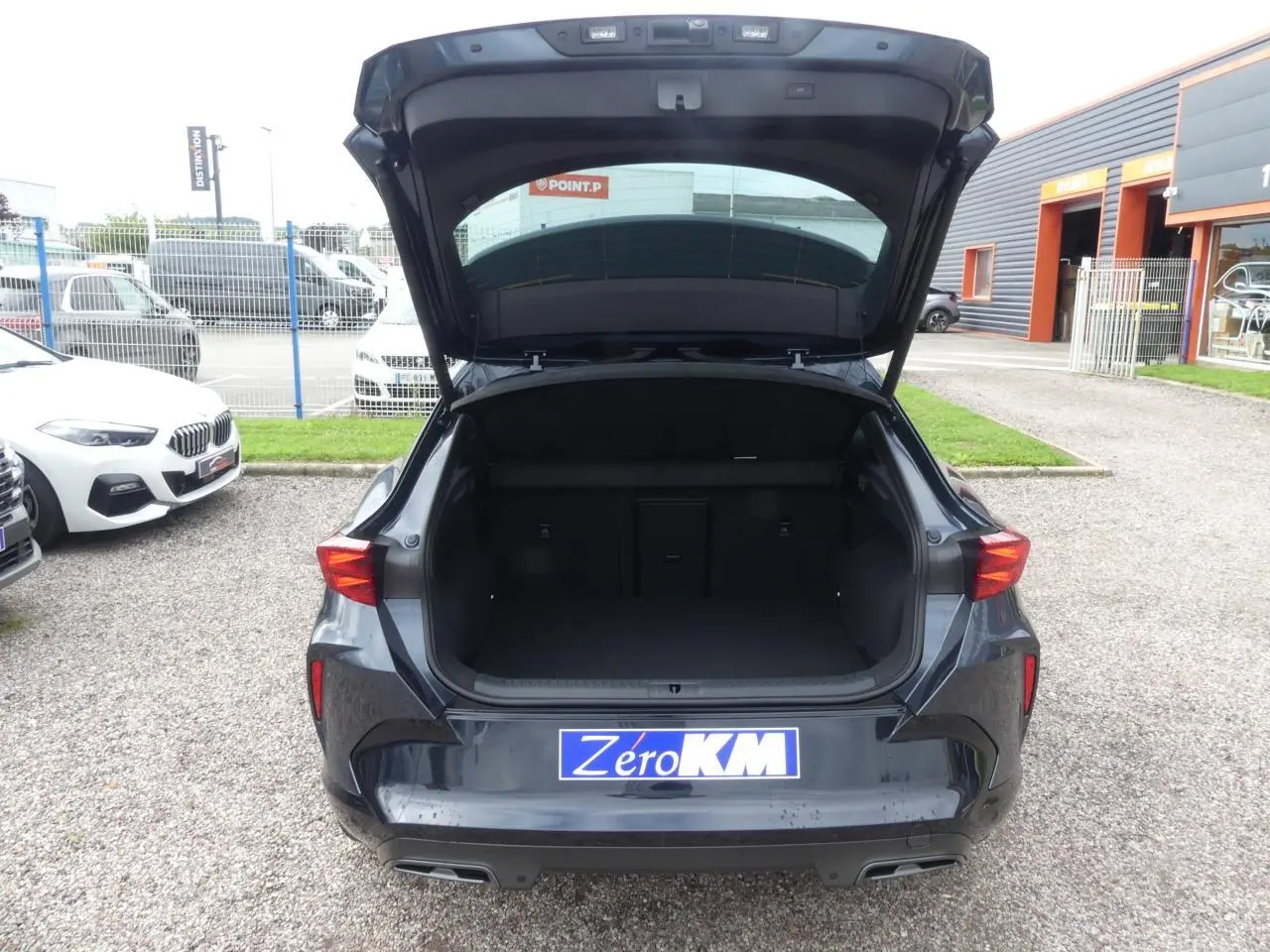 Vue arrière d'un CUPRA Formentor gris Graphene avec coffre ouvert et double sortie d'échappement noire visible.