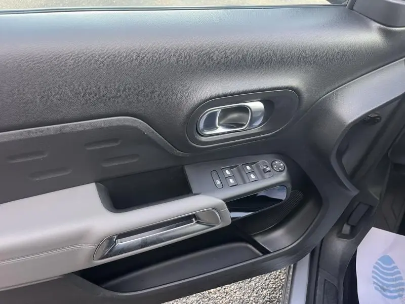 Vue rapprochée de la porte avant gauche du Citroën C5 Aircross gris Platinium, avec commandes électriques et poignée chromée.