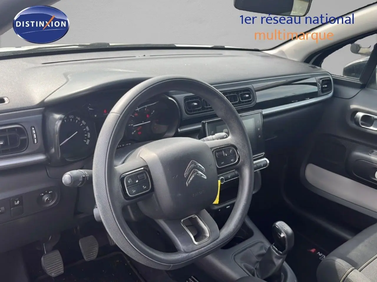 Intérieur de la Citroën C3 2018 vu côté conducteur, tableau de bord noir avec volant multifonction et boîte manuelle.