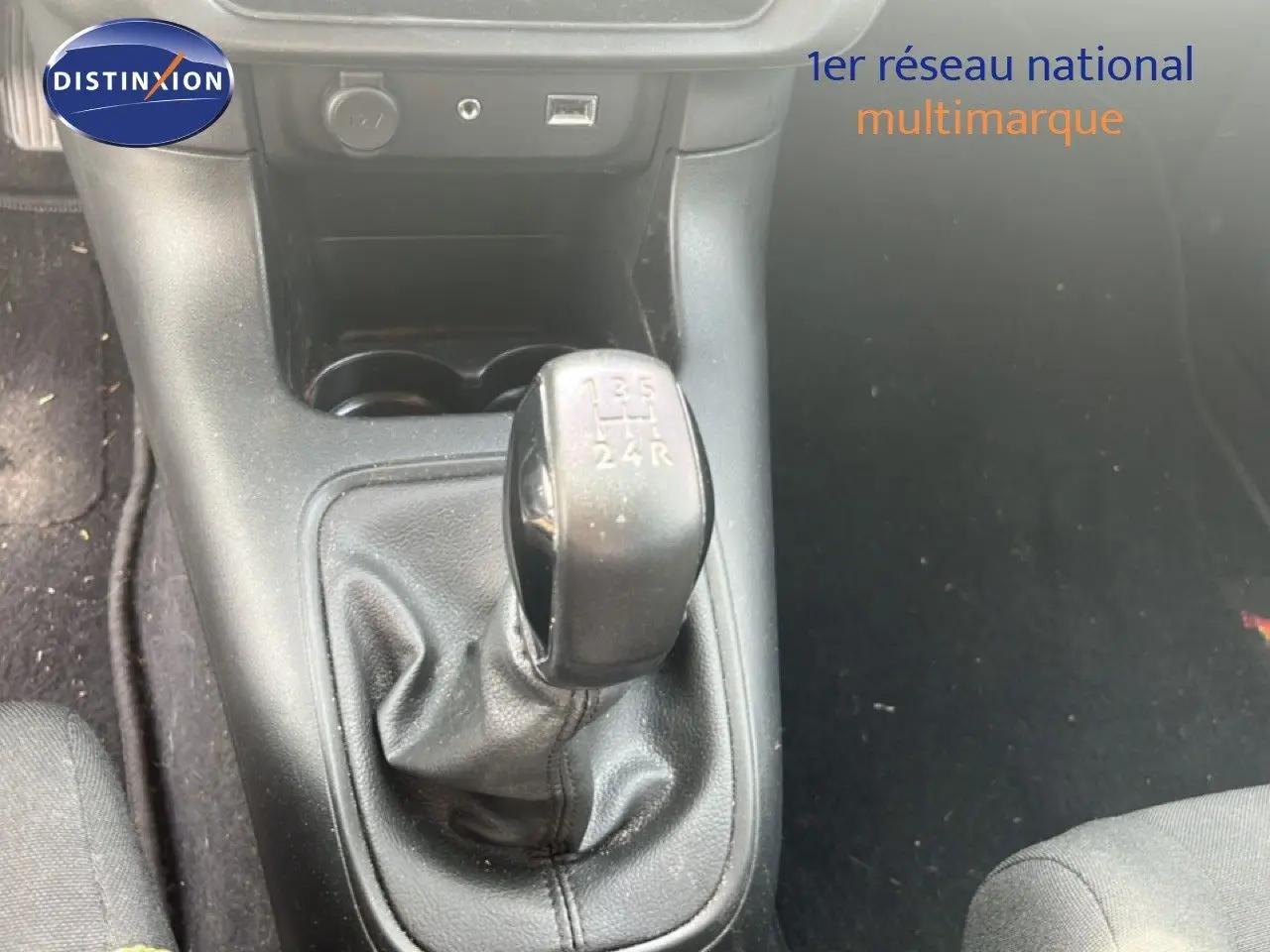 Le levier de vitesses manuel noir de la Citroën C3 blanche, vu en gros plan depuis l'intérieur avant.