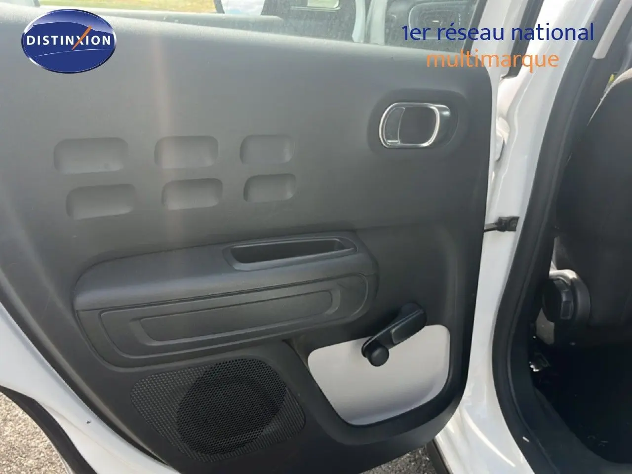 Vue intérieure de la porte arrière gauche d'une Citroën C3 blanche 2018 avec poignée de vitre manuelle et haut-parleur intégré.