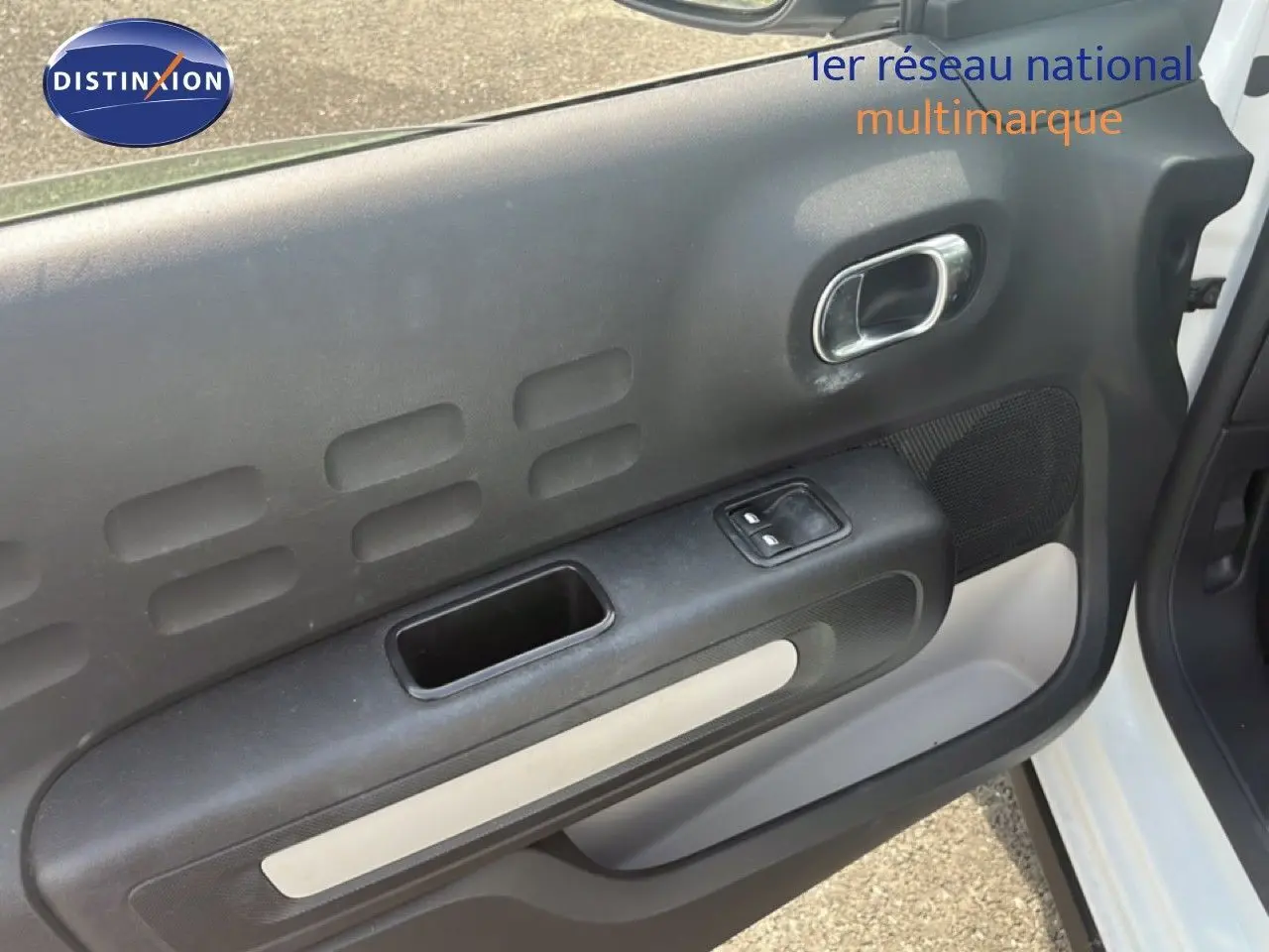 Vue rapprochée de la porte avant gauche blanche d'une Citroën C3 2018, mettant en valeur la poignée et les commandes électriques.