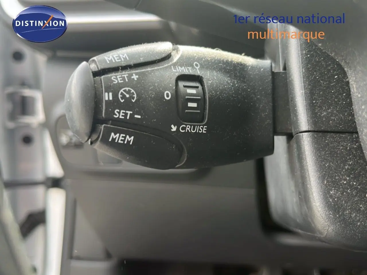 Gros plan sur la commande de régulateur de vitesse noire dans l'habitacle d'une Citroën C3 blanche de 2018.
