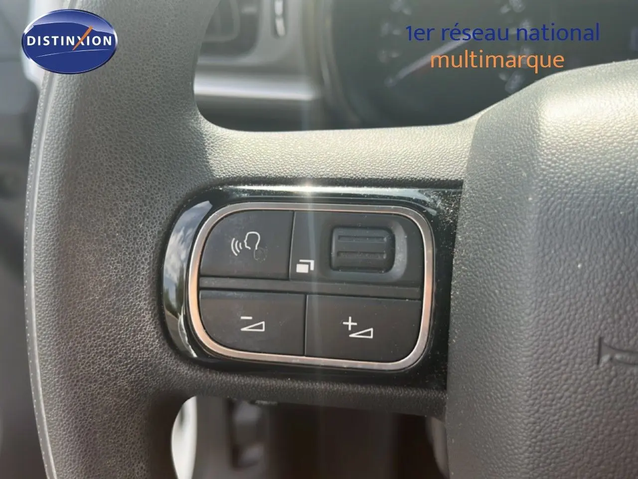 Gros plan sur les commandes de volume et téléphone au volant d'une Citroën C3 blanche, version 2018.