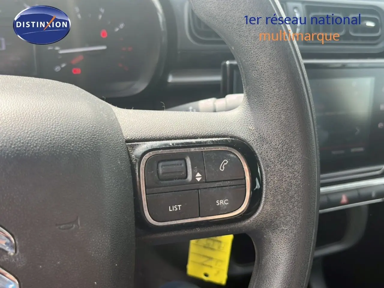 Gros plan sur les commandes au volant d'une Citroën C3 2018 essence, mettant en valeur les boutons de gestion audio et téléphone.