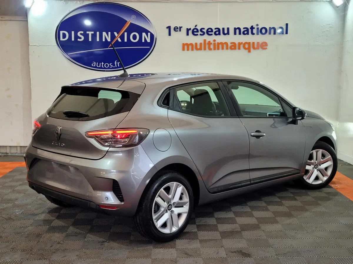 Renault Clio Evolution Blue dCi 100 2025 gris foncé vue 3/4 arrière droit avec feux LED allumés en intérieur showroom.