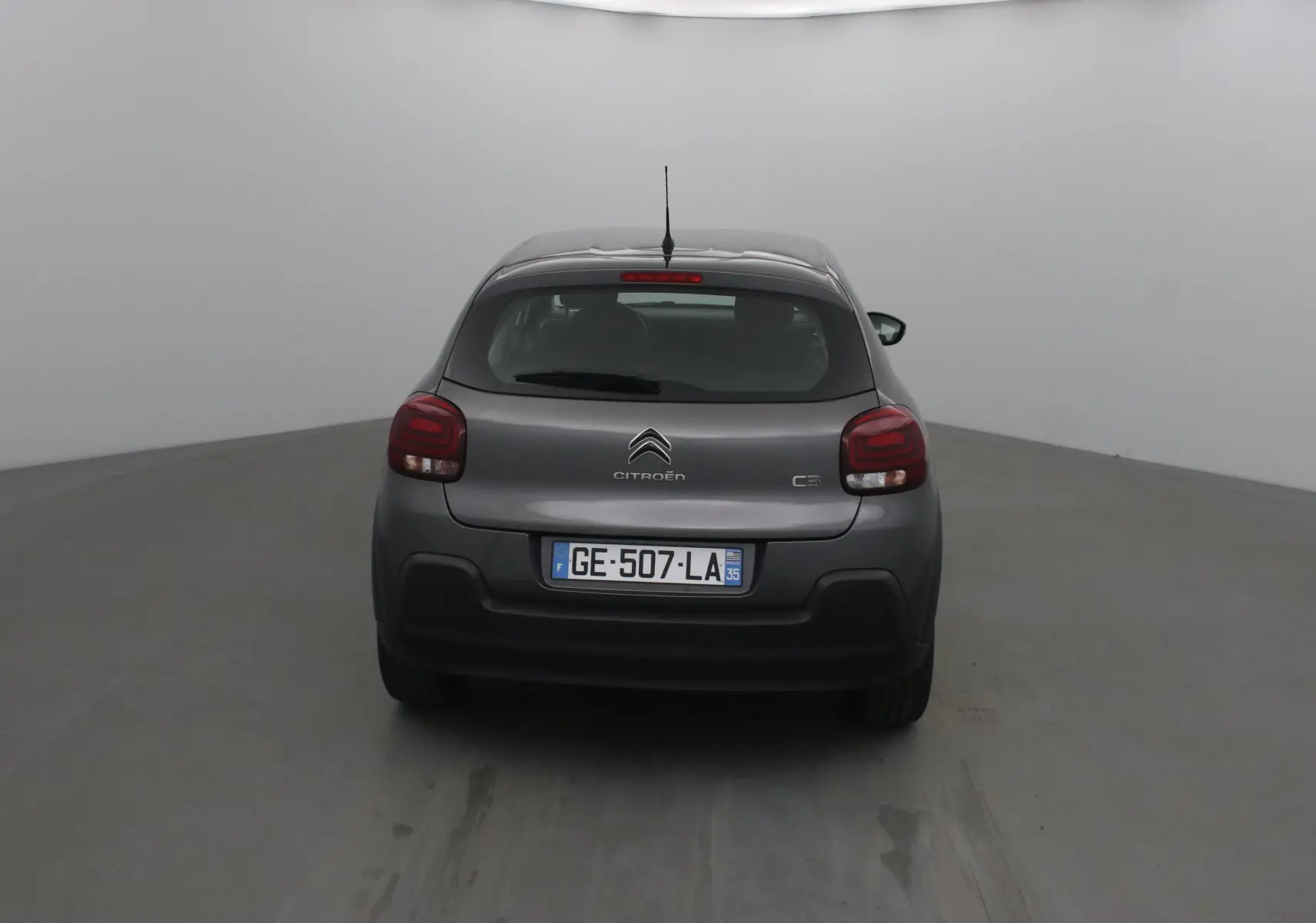 Vue arrière d'une Citroën C3 gris platinium 2022, avec feux arrière rouges et plaque d'immatriculation française visible.