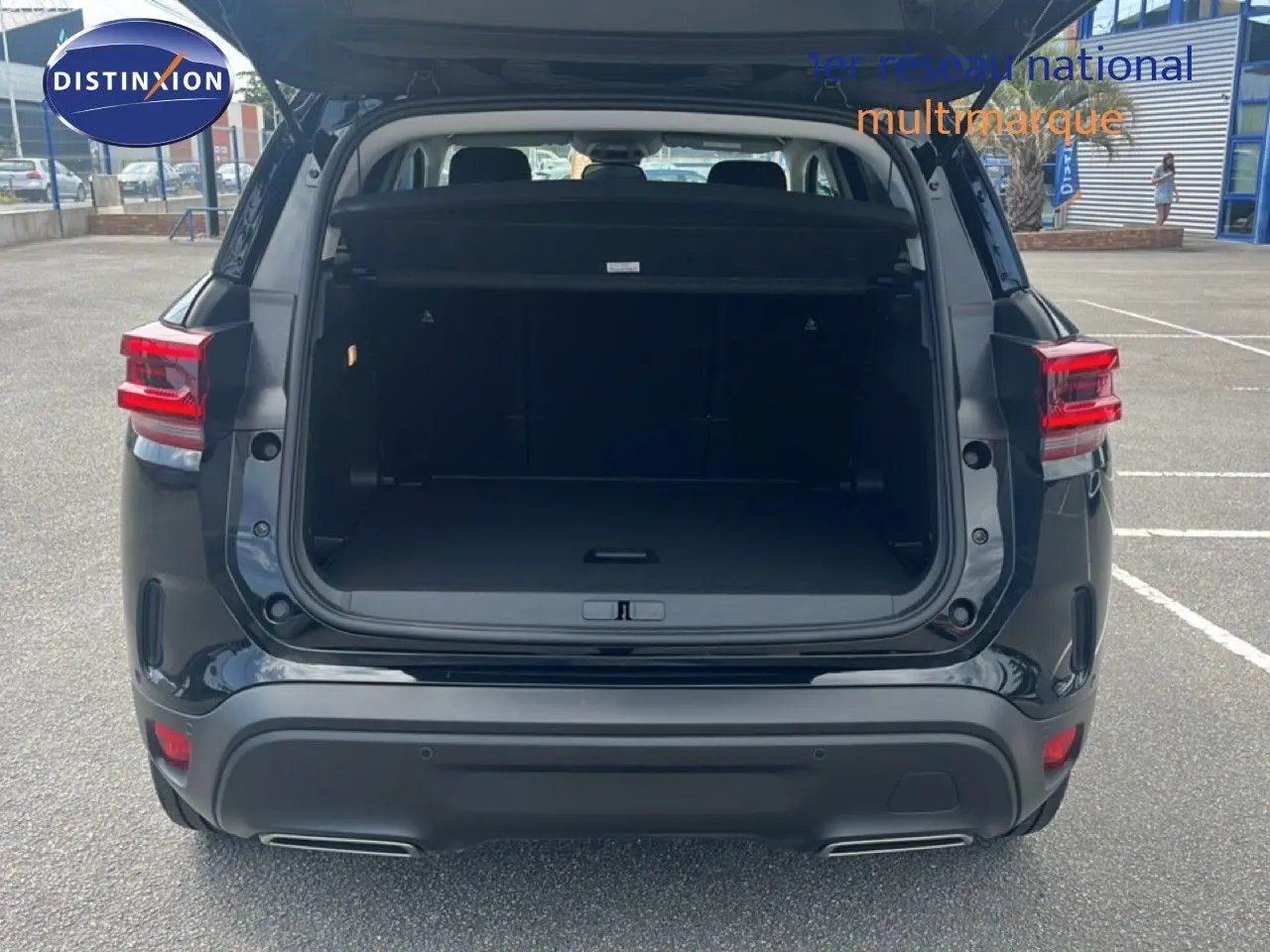 Vue arrière d'un Citroën C5 Aircross noir métal 2025 avec coffre ouvert et feux arrière allumés.