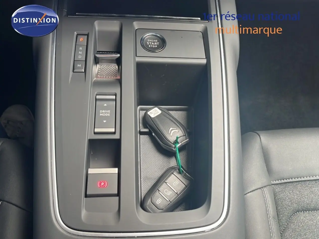 Vue plongeante sur la console centrale noire du Citroën C5 Aircross 2025 avec clés, bouton start et commandes de boîte auto.