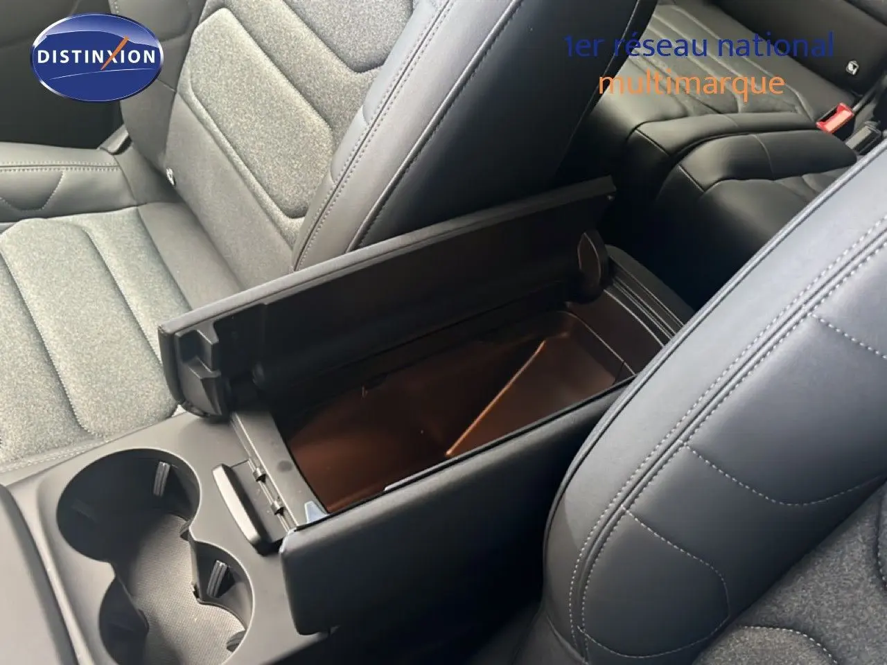 Vue intérieure rapprochée du coffre central ouvert entre les sièges avant en tissu gris et cuir noir du Citroën C5 Aircross 2025.