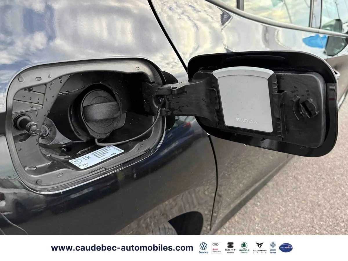 Trappe de carburant ouverte côté gauche d'une Skoda Fabia noire, bouchon essence visible avec logo Skoda.
