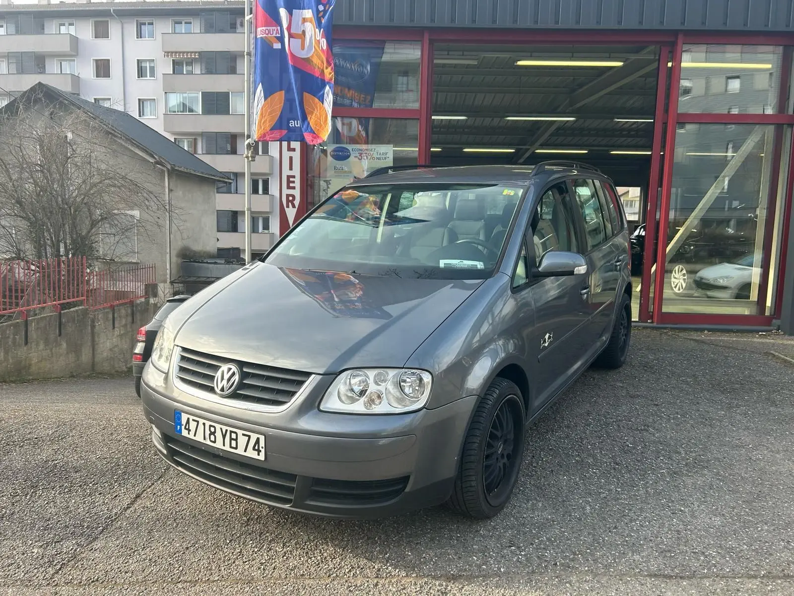 Volkswagen Touran gris 2004 en 3/4 avant droit, avec jantes noires et calandre distinctive Volkswagen.