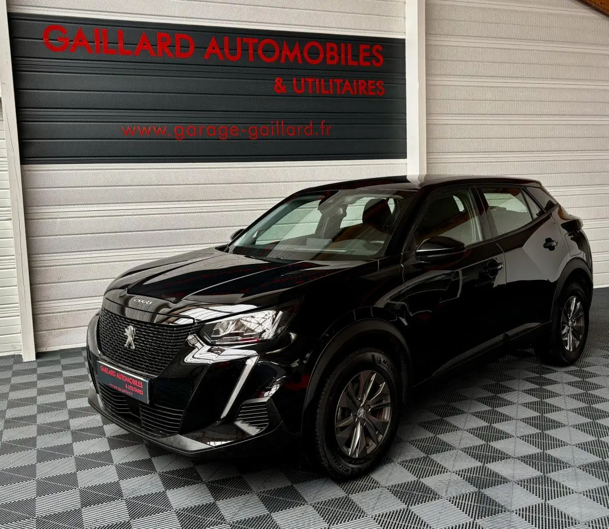 Peugeot 2008 noir vue 3/4 avant droit, avec calandre distinctive et phares LED dans un showroom.