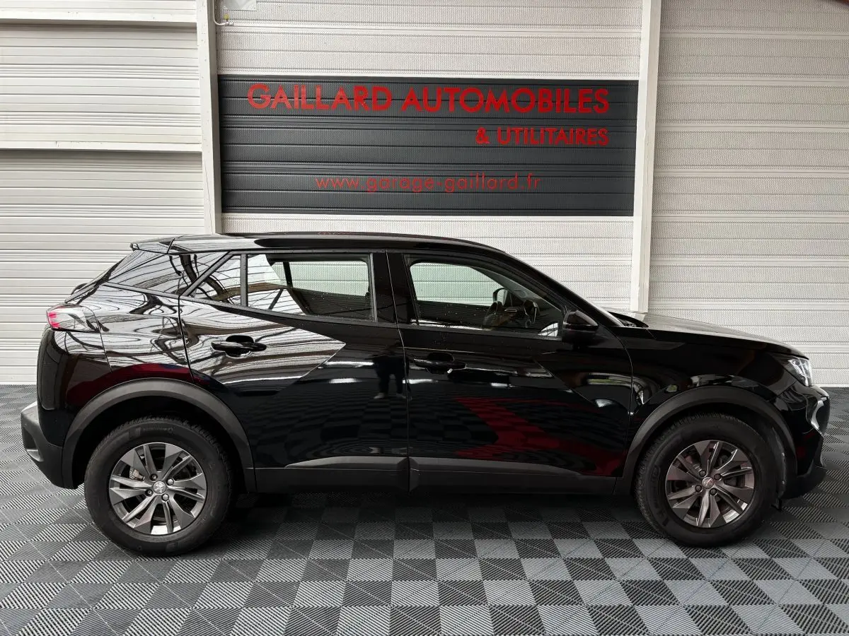 Profil côté gauche d'un Peugeot 2008 noir 2021 garé en intérieur avec reflets sur la carrosserie.