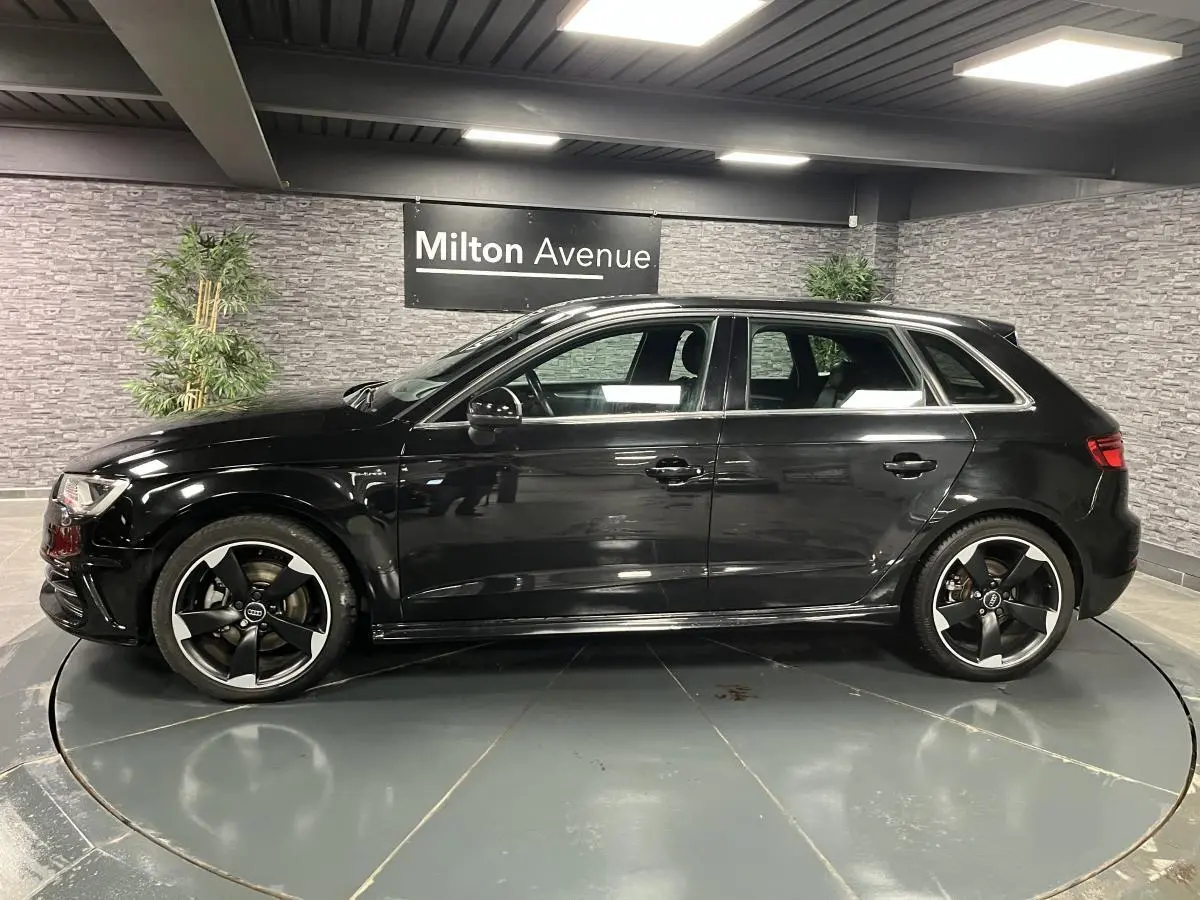 Profil côté gauche d'une Audi A3 1.4 TFSI e-tron S line noire avec jantes Audi Sport 18 pouces en intérieur showroom.