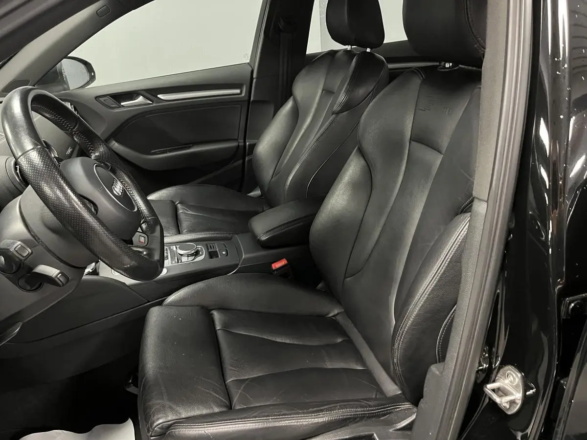 Intérieur noir de l'Audi A3 1.4 TFSI e-tron S line, vue côté conducteur avec sièges sport cuir et volant multifonction.