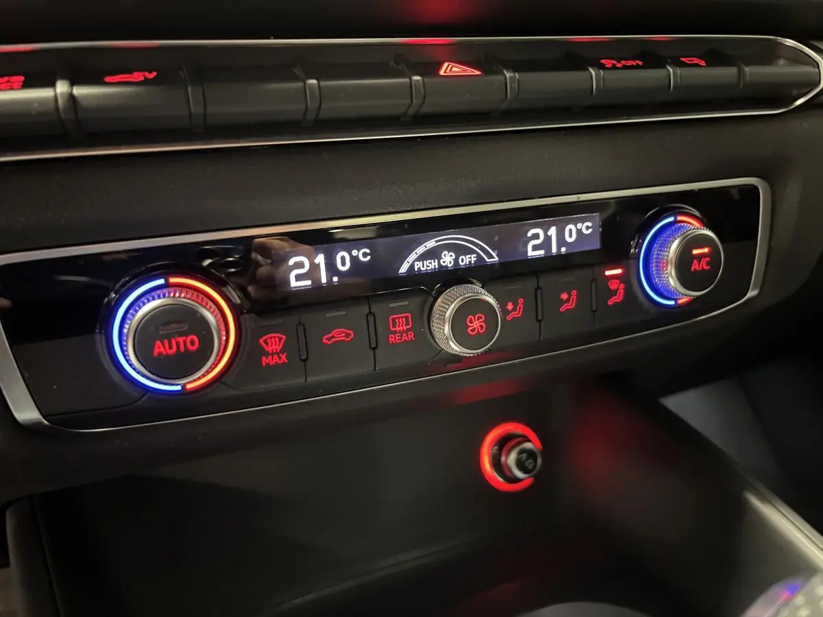 Détail de la console de climatisation automatique de l'Audi A3 1.4 TFSI e-tron S line 2015 avec affichage digital et boutons rétroéclairés rouge et bleu.