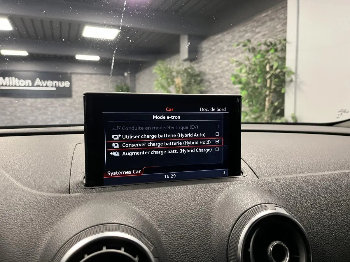 Écran central du tableau de bord d'une Audi A3 1.4 TFSI e-tron S line affichant les modes de charge batterie hybride.