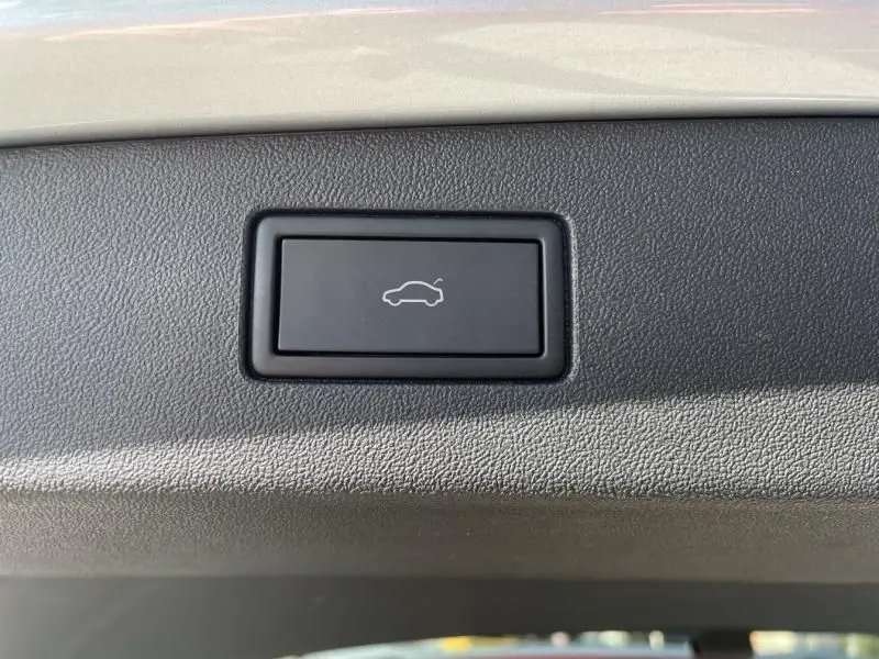 Bouton d'ouverture du coffre sur le hayon d'un Volkswagen Tiguan 1.5 eHybrid gris métal, vue en gros plan.