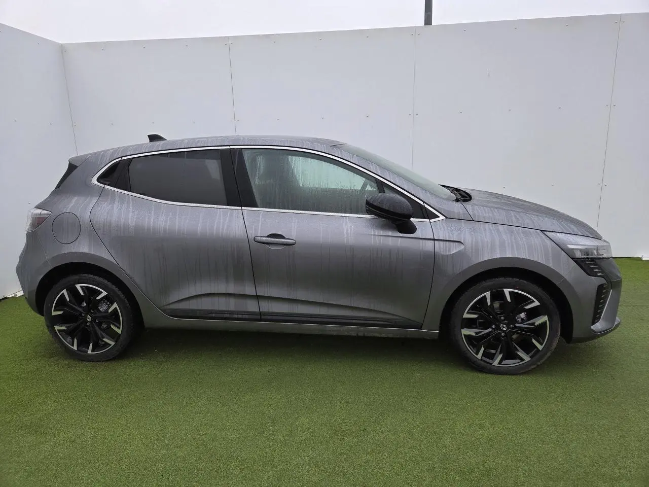 Profil droit de la Renault Clio 2025 gris schiste métal avec jantes alliage noires et vitres surteintées.