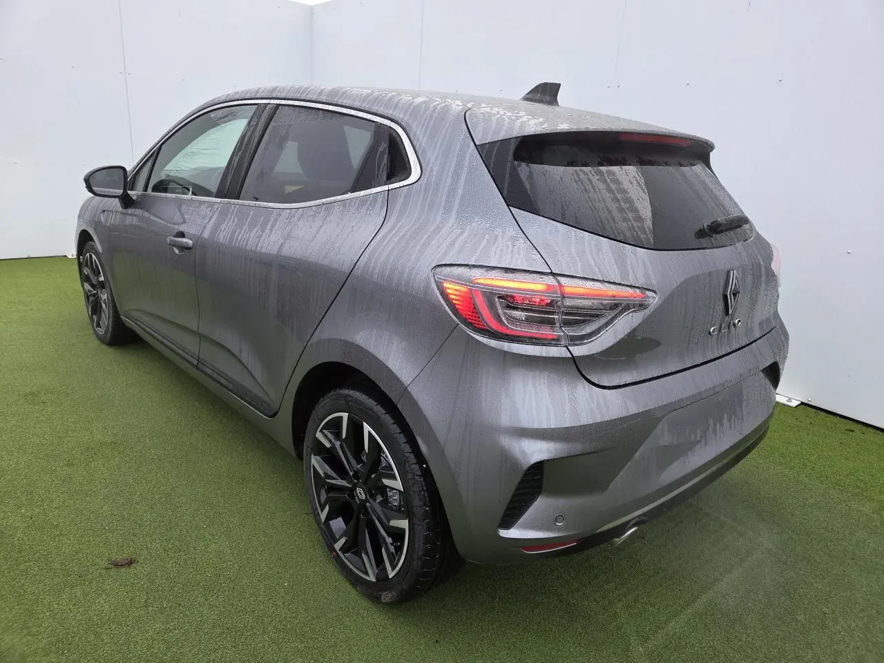 Vue 3/4 arrière droite d'une Renault Clio gris schiste métal avec jantes alliage noires et vitres surteintées.