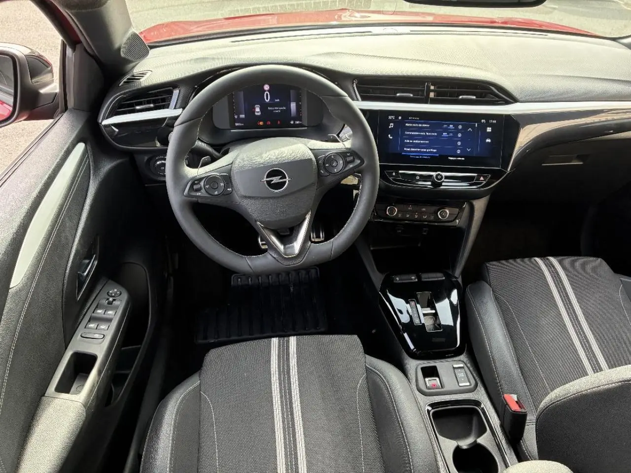 Vue intérieure de face de l’Opel Corsa 2025 hybride, montrant le volant, tableau de bord digital et console centrale noire brillante.