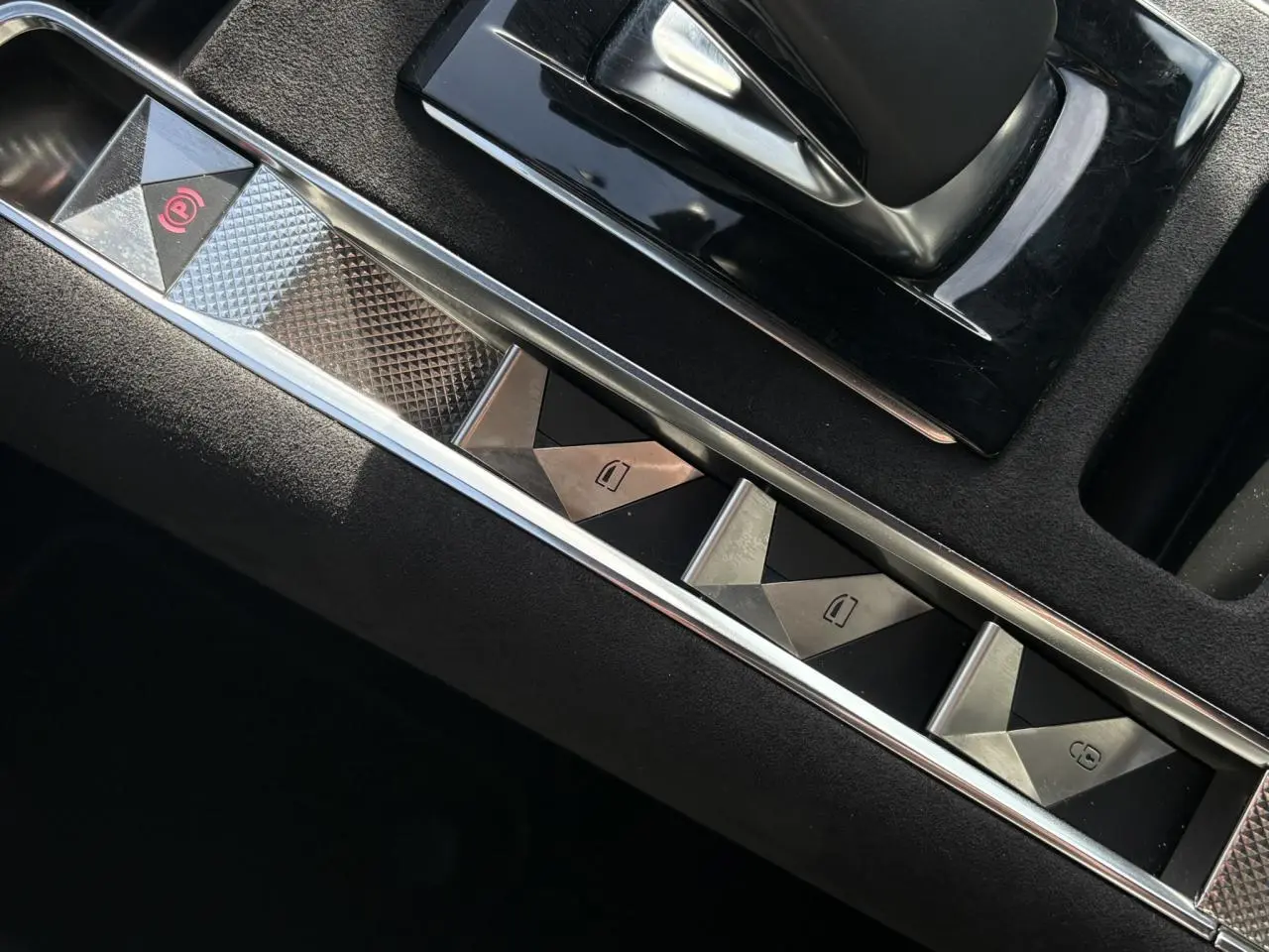 Gros plan sur les commandes de lève-vitres et frein de stationnement du DS7 1.6 E-Tense Cristal Pearl, intérieur noir Alcantara.
