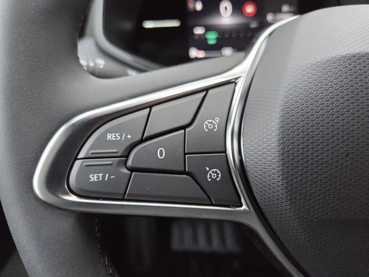 Gros plan sur les commandes de régulateur de vitesse au volant noir de la Renault Clio V Gris Schiste 2025.