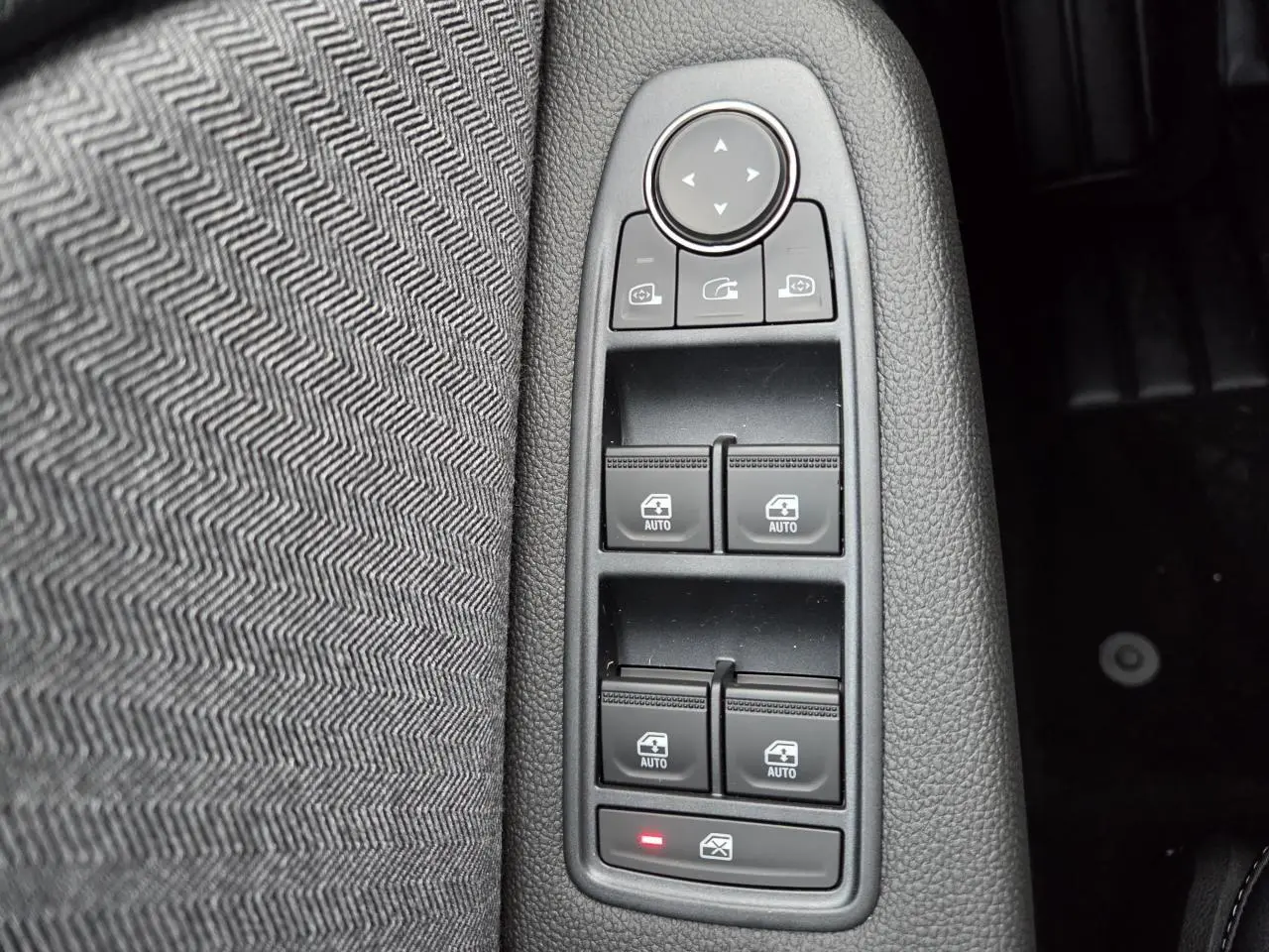 Gros plan sur les commandes des vitres électriques et rétroviseurs dans l'habitacle gris mélangé de la Renault Clio V 2025.