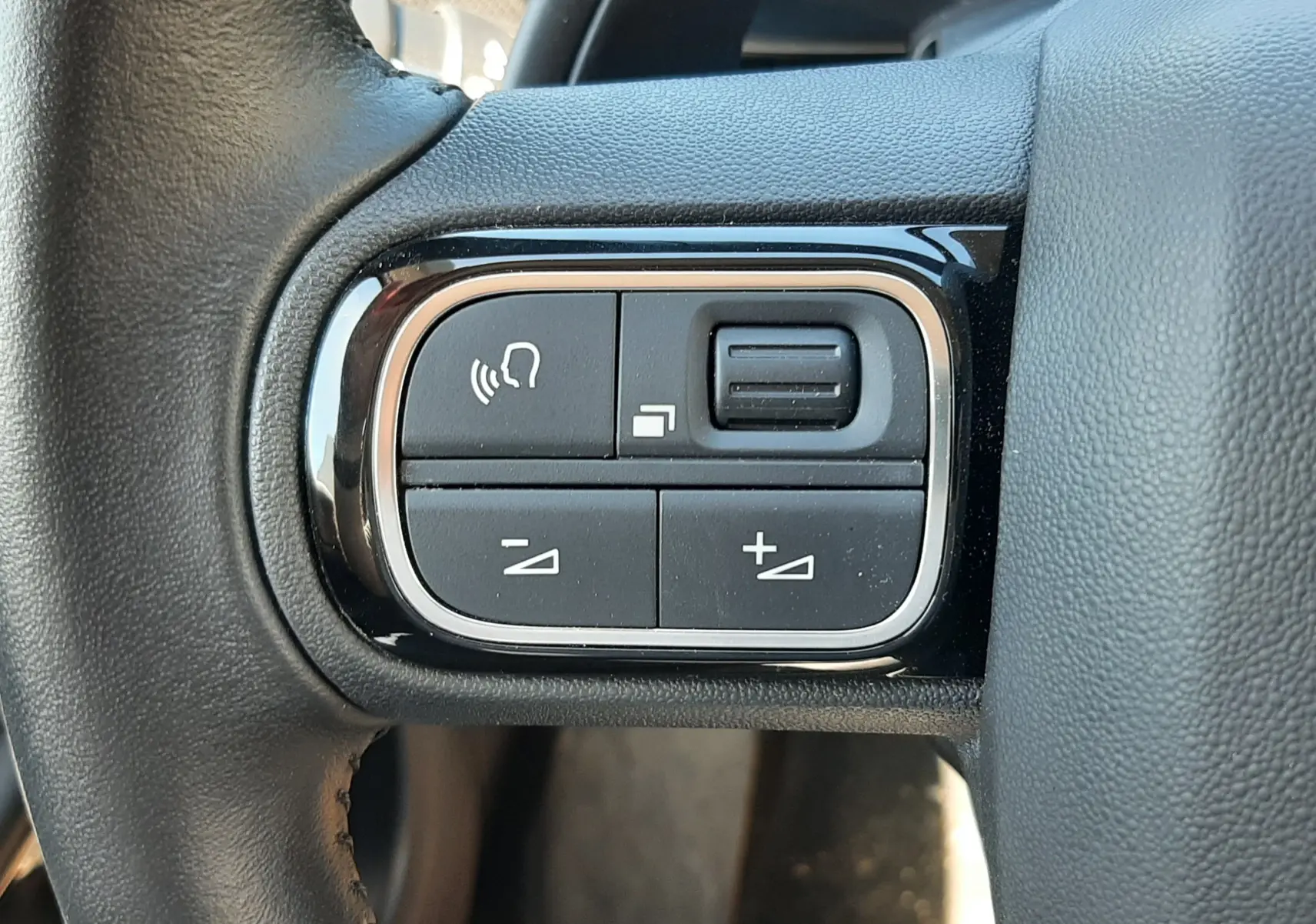Gros plan sur les commandes noires du volant cuir du Citroën C5 Aircross Hybrid 136 e-DCS6 Max, finition 2024.