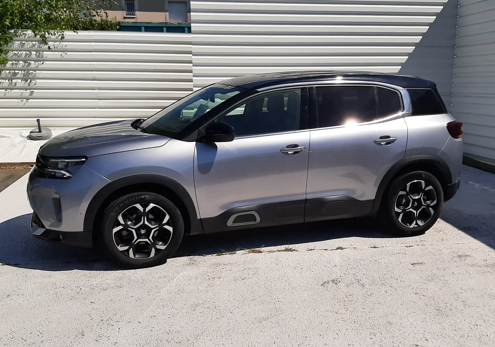 Vue de profil côté gauche du Citroën C5 Aircross Hybrid gris acier avec toit noir, roues à jantes noires et détails noirs.