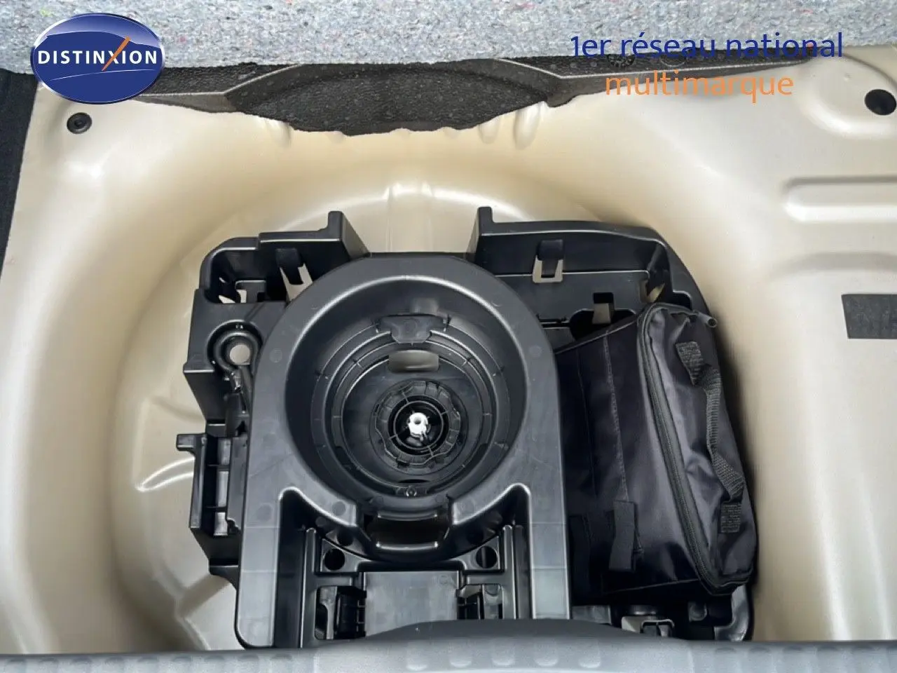 Vue plongeante sur le compartiment de roue de secours d'une Citroën C3 gris Artense métal, avec kit de réparation visible.