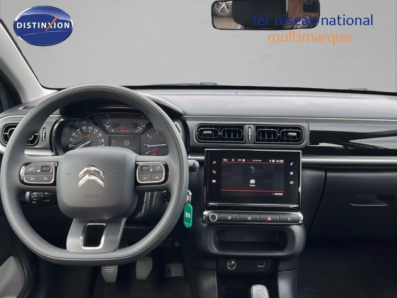 Vue intérieure frontale du tableau de bord de la Citroën C3 2024, avec volant gris et écran tactile central.