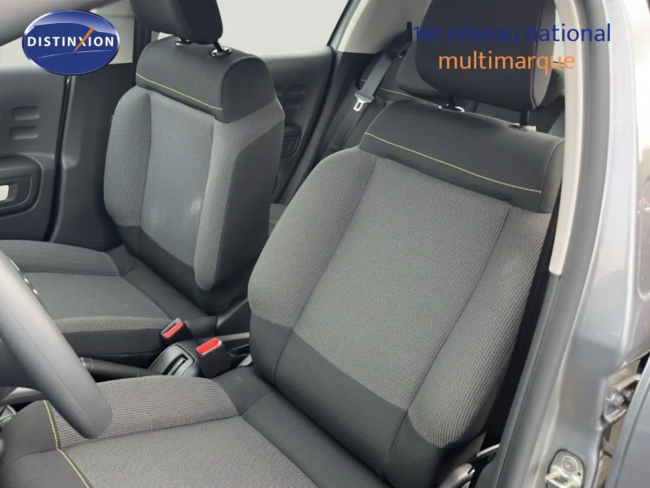 Vue intérieure côté conducteur de la Citroën C3 2024 gris Artense, sièges tissu gris avec surpiqûres jaunes.