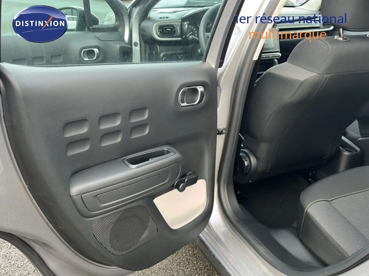 Vue intérieure côté gauche de la porte arrière ouverte d'une Citroën C3 gris Artense 2024, avec sellerie noire et détails clairs.