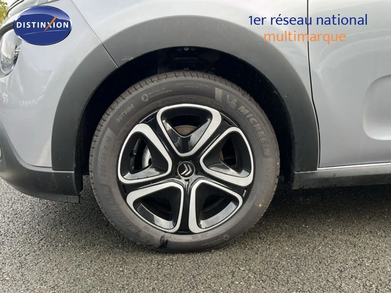 Gros plan sur la roue avant gauche d'une Citroën C3 2024 gris Artense métal avec jante alliage noire et argentée.