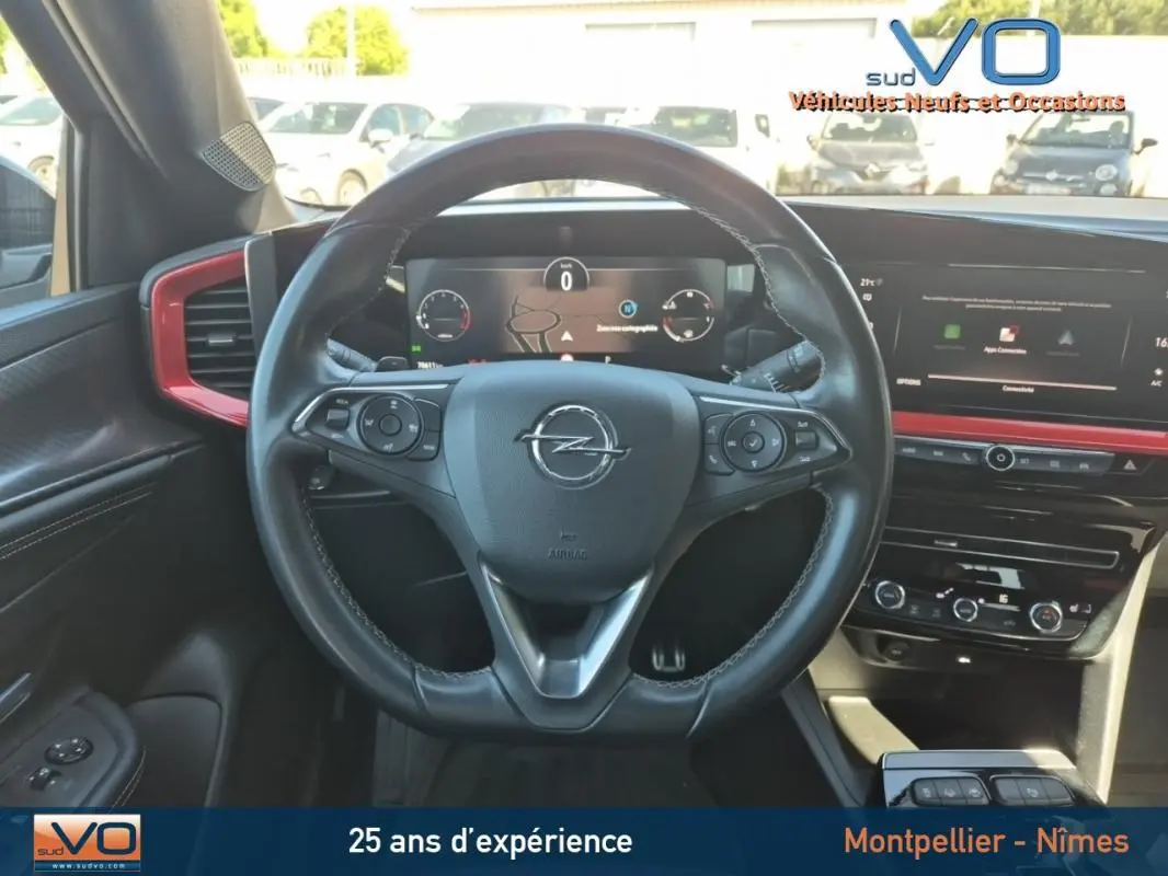Vue intérieure centrée sur le volant cuir de l'Opel Mokka 2022 avec tableau de bord numérique et écran tactile rouge.